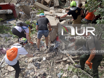 Locals are helping remove the rubble at a section of a five-storey apartment building in the Shevchenkivskyi district destroyed by the Russi...