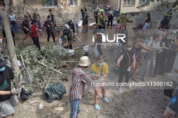 Locals are helping remove the rubble at a section of a five-storey apartment building in the Shevchenkivskyi district destroyed by the Russi...