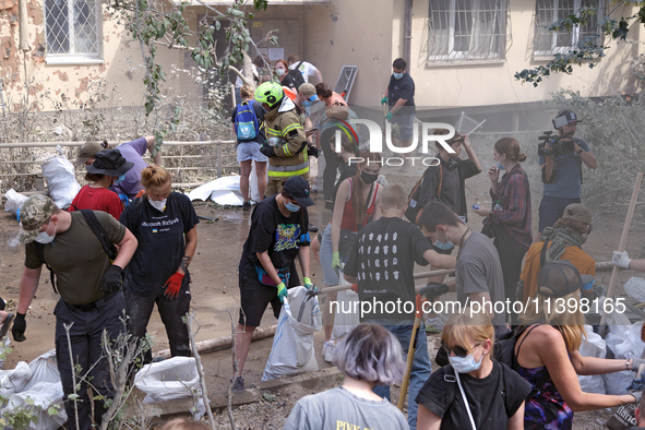 Locals are helping remove the rubble at a section of a five-storey apartment building in the Shevchenkivskyi district destroyed by the Russi...