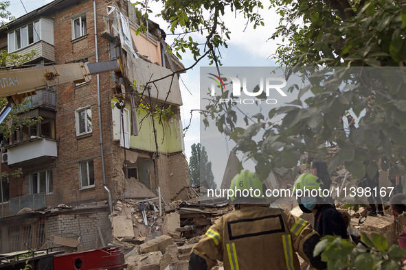 Rescue workers are staying outside a section of a five-storey apartment block in the Shevchenkivskyi district destroyed by the Russian missi...