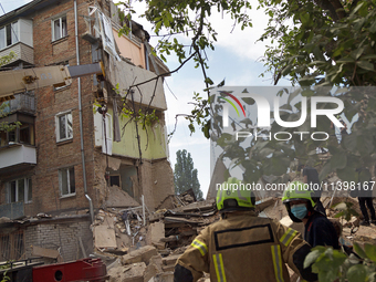 Rescue workers are staying outside a section of a five-storey apartment block in the Shevchenkivskyi district destroyed by the Russian missi...