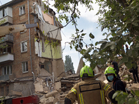 Rescue workers are staying outside a section of a five-storey apartment block in the Shevchenkivskyi district destroyed by the Russian missi...