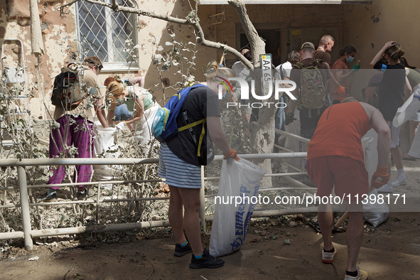 Locals are helping remove the rubble at a section of a five-storey apartment building in the Shevchenkivskyi district destroyed by the Russi...