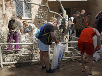 Locals are helping remove the rubble at a section of a five-storey apartment building in the Shevchenkivskyi district destroyed by the Russi...