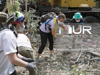 Locals are helping remove the rubble at a section of a five-storey apartment building in the Shevchenkivskyi district destroyed by the Russi...