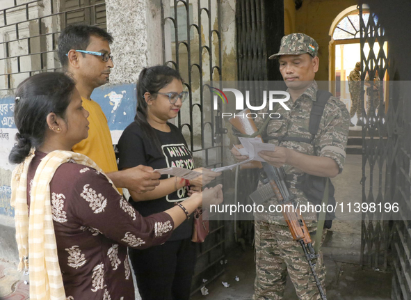 Indian paramilitary troopers are checking a voter's slip before she casts her vote outside a polling station during the by-election in the M...