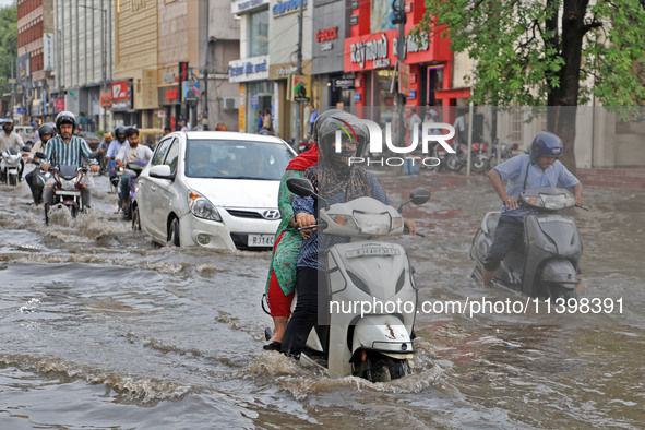 Commuters are wading through a waterlogged road during the monsoon rain in Jaipur, Rajasthan, India, on July 10, 2024. 