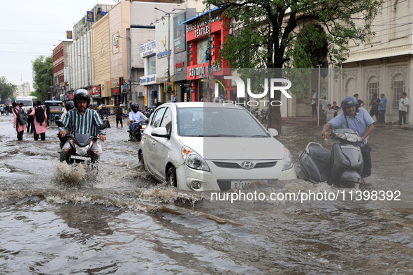 Commuters are wading through a waterlogged road during the monsoon rain in Jaipur, Rajasthan, India, on July 10, 2024. 