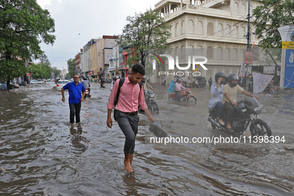 Commuters are wading through a waterlogged road during the monsoon rain in Jaipur, Rajasthan, India, on July 10, 2024. 