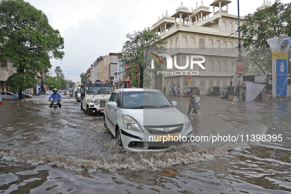 Commuters are wading through a waterlogged road during the monsoon rain in Jaipur, Rajasthan, India, on July 10, 2024. 