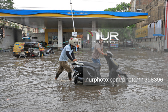 Commuters are wading through a waterlogged road during the monsoon rain in Jaipur, Rajasthan, India, on July 10, 2024. 