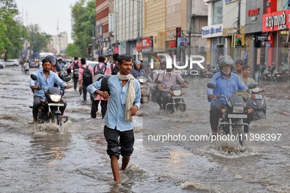 Commuters are wading through a waterlogged road during the monsoon rain in Jaipur, Rajasthan, India, on July 10, 2024. 