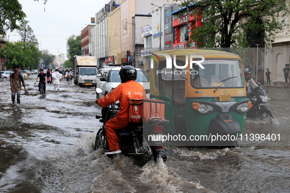 Commuters are wading through a waterlogged road during the monsoon rain in Jaipur, Rajasthan, India, on July 10, 2024. 