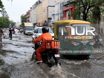 Commuters are wading through a waterlogged road during the monsoon rain in Jaipur, Rajasthan, India, on July 10, 2024. (