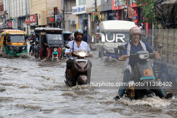 Commuters are wading through a waterlogged road during the monsoon rain in Jaipur, Rajasthan, India, on July 10, 2024. 