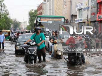 Commuters are wading through a waterlogged road during the monsoon rain in Jaipur, Rajasthan, India, on July 10, 2024. (