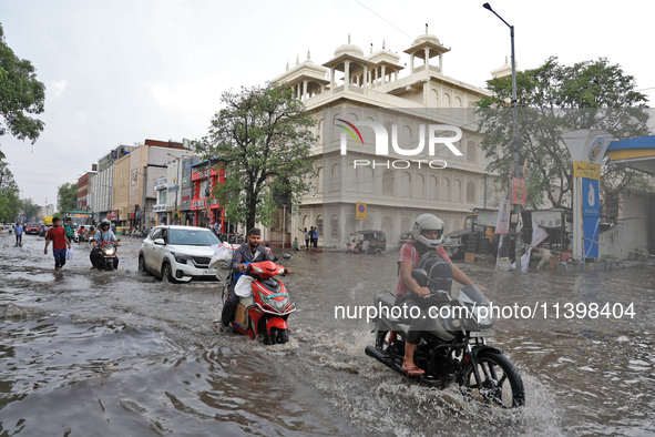 Commuters are wading through a waterlogged road during the monsoon rain in Jaipur, Rajasthan, India, on July 10, 2024. 