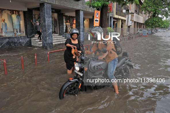 Commuters are wading through a waterlogged road during the monsoon rain in Jaipur, Rajasthan, India, on July 10, 2024. 