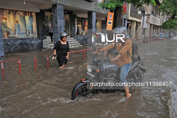 Commuters are wading through a waterlogged road during the monsoon rain in Jaipur, Rajasthan, India, on July 10, 2024. 