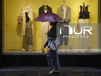 A woman is covering herself from the rain with an umbrella in the streets of Mexico City. (