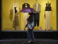 A woman is covering herself from the rain with an umbrella in the streets of Mexico City. (