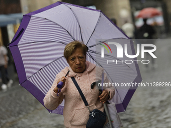 A woman is covering herself from the rain with an umbrella in the streets of Mexico City. (