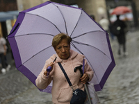 A woman is covering herself from the rain with an umbrella in the streets of Mexico City. (