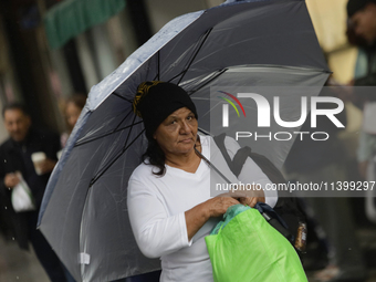 A woman is covering herself from the rain with an umbrella in the streets of Mexico City. (