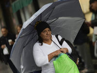 A woman is covering herself from the rain with an umbrella in the streets of Mexico City. (