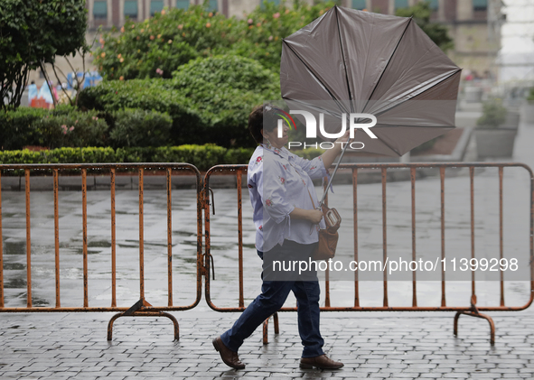 A woman is covering herself from the rain with an umbrella in the streets of Mexico City. 