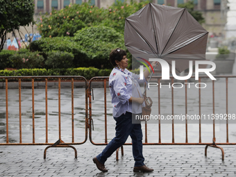 A woman is covering herself from the rain with an umbrella in the streets of Mexico City. (