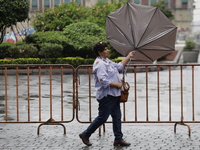 A woman is covering herself from the rain with an umbrella in the streets of Mexico City. (