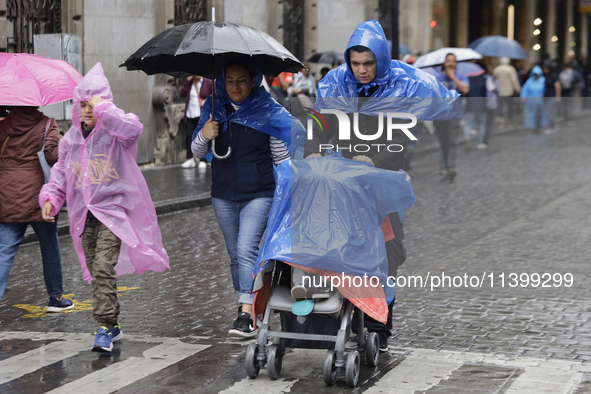 People are covering themselves from the rain with raincoats on the streets of Mexico City. 