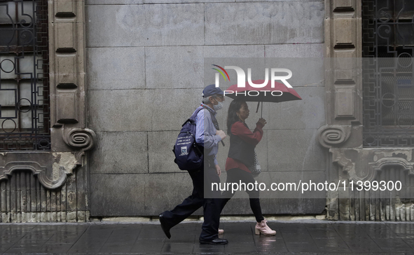 People are walking in the rain on the streets of Mexico City. 