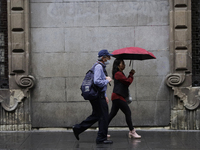 People are walking in the rain on the streets of Mexico City. (