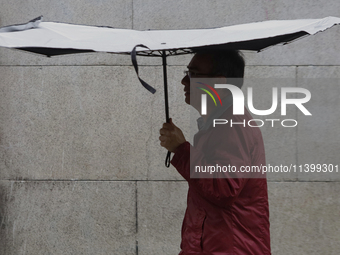 A man is covering himself from the rain with an umbrella in the streets of Mexico City. (