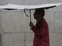 A man is covering himself from the rain with an umbrella in the streets of Mexico City. (