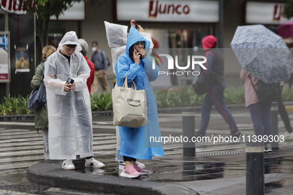 People are covering themselves from the rain with raincoats on the streets of Mexico City. 