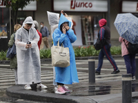 People are covering themselves from the rain with raincoats on the streets of Mexico City. (