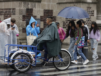 People are walking in the rain on the streets of Mexico City. (