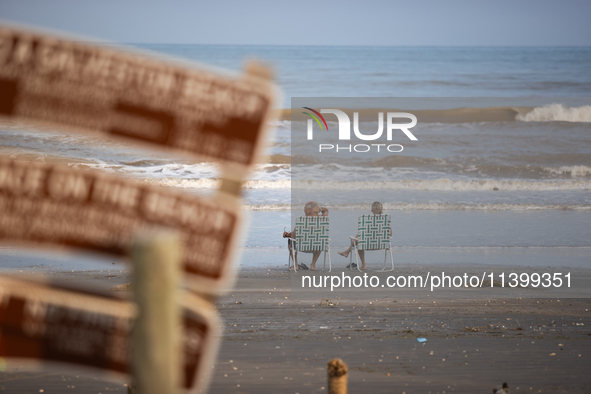 A couple is sitting on Pirates Beach in Galveston, Texas, on July 10, 2024. 