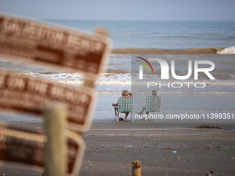 A couple is sitting on Pirates Beach in Galveston, Texas, on July 10, 2024. (