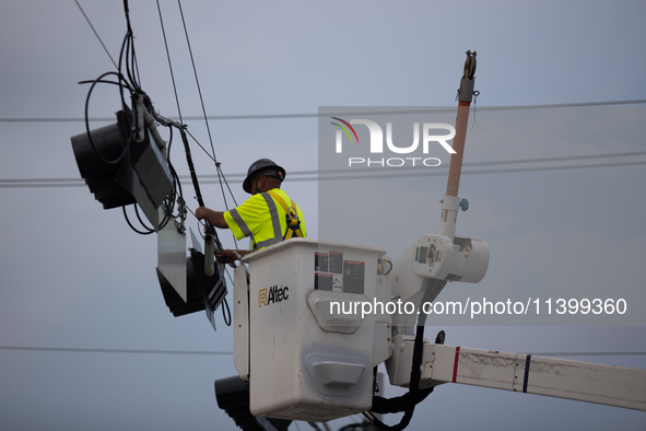 An electrical lineman is working on one of the many broken traffic lights in the Galveston area on July 10, 2024. 