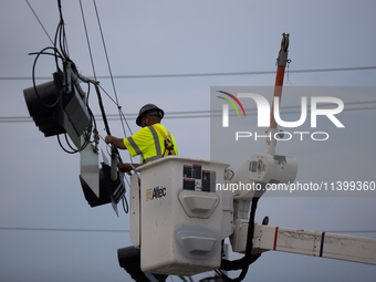 An electrical lineman is working on one of the many broken traffic lights in the Galveston area on July 10, 2024. (