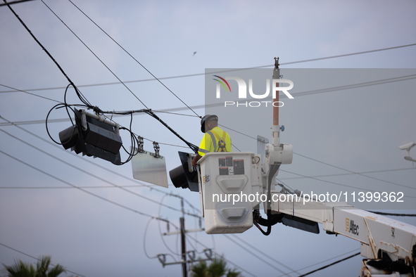 An electrical lineman is working on one of the many broken traffic lights in the Galveston area on July 10, 2024. 