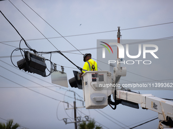 An electrical lineman is working on one of the many broken traffic lights in the Galveston area on July 10, 2024. (