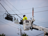 An electrical lineman is working on one of the many broken traffic lights in the Galveston area on July 10, 2024. (