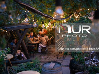 People are staying at an outdoor cafe in a courtyard in Lviv, Ukraine, on July 5, 2024. NO USE RUSSIA. NO USE BELARUS. (