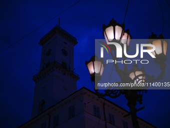 A lamppost is shining near the Lviv Town Hall at night in Lviv, Ukraine, on July 5, 2024. NO USE RUSSIA. NO USE BELARUS. (