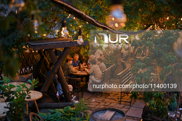 People are staying at an outdoor cafe in a courtyard in Lviv, Ukraine, on July 5, 2024. NO USE RUSSIA. NO USE BELARUS. 